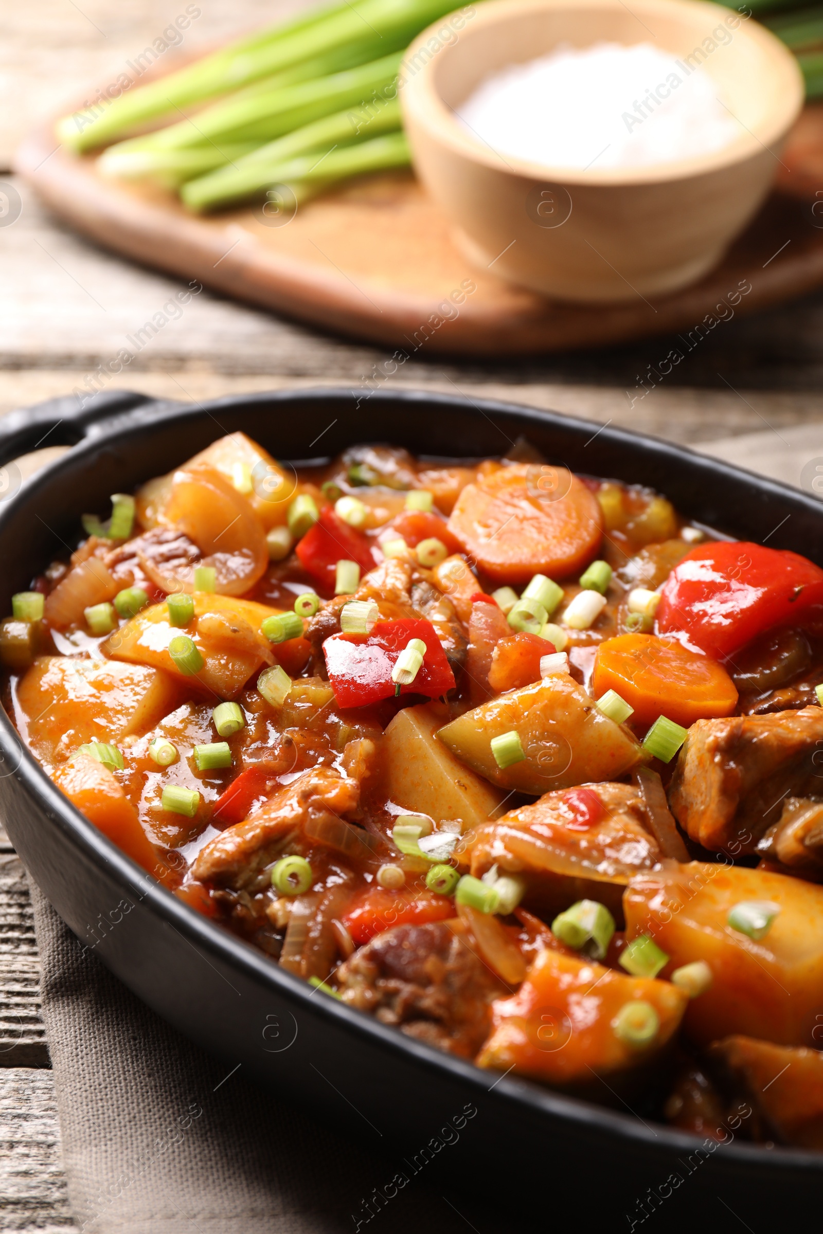 Photo of Delicious stew with vegetables in baking dish on wooden table, closeup