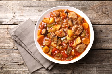 Photo of Delicious stew with vegetables in bowl on wooden table, top view