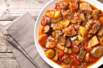 Photo of Delicious stew with vegetables in bowl on wooden table, top view