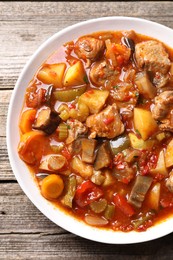 Photo of Delicious stew with vegetables in bowl on wooden table, top view