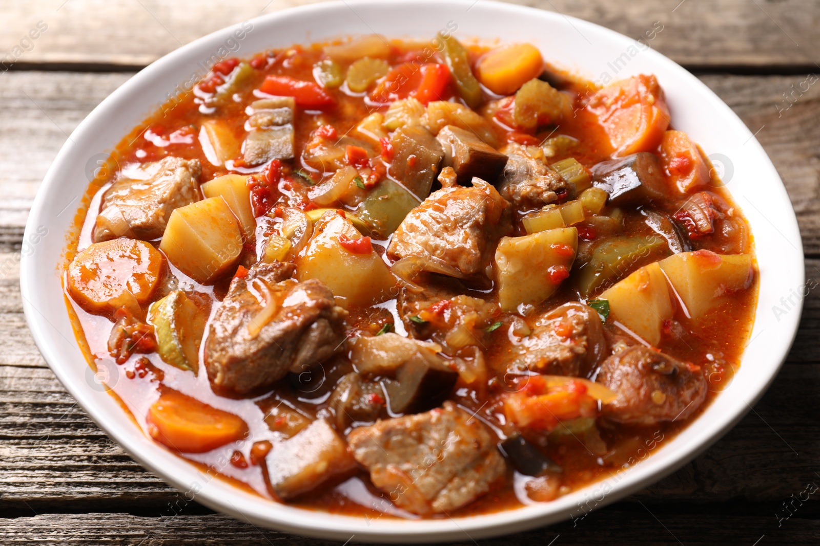 Photo of Delicious stew with vegetables in bowl on wooden table, closeup