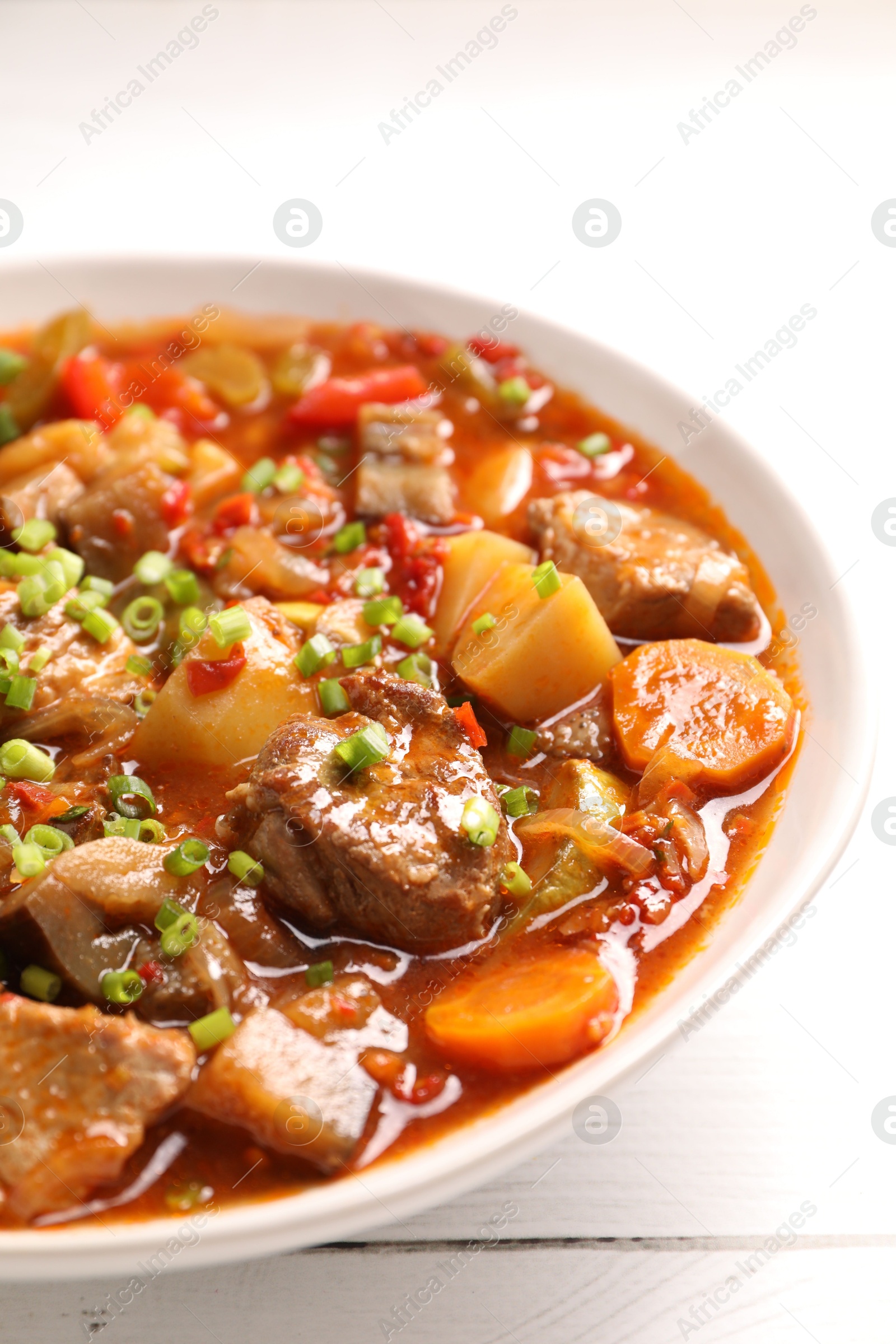 Photo of Delicious stew with vegetables in bowl on white wooden table, closeup