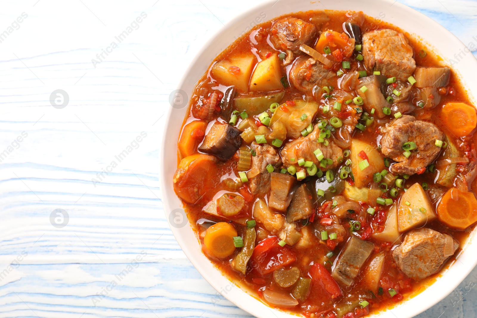 Photo of Delicious stew with vegetables in bowl on light blue wooden background, top view