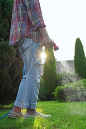 Man watering green grass on lawn in backyard, closeup