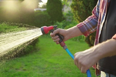 Man watering lawn with hose in backyard, closeup