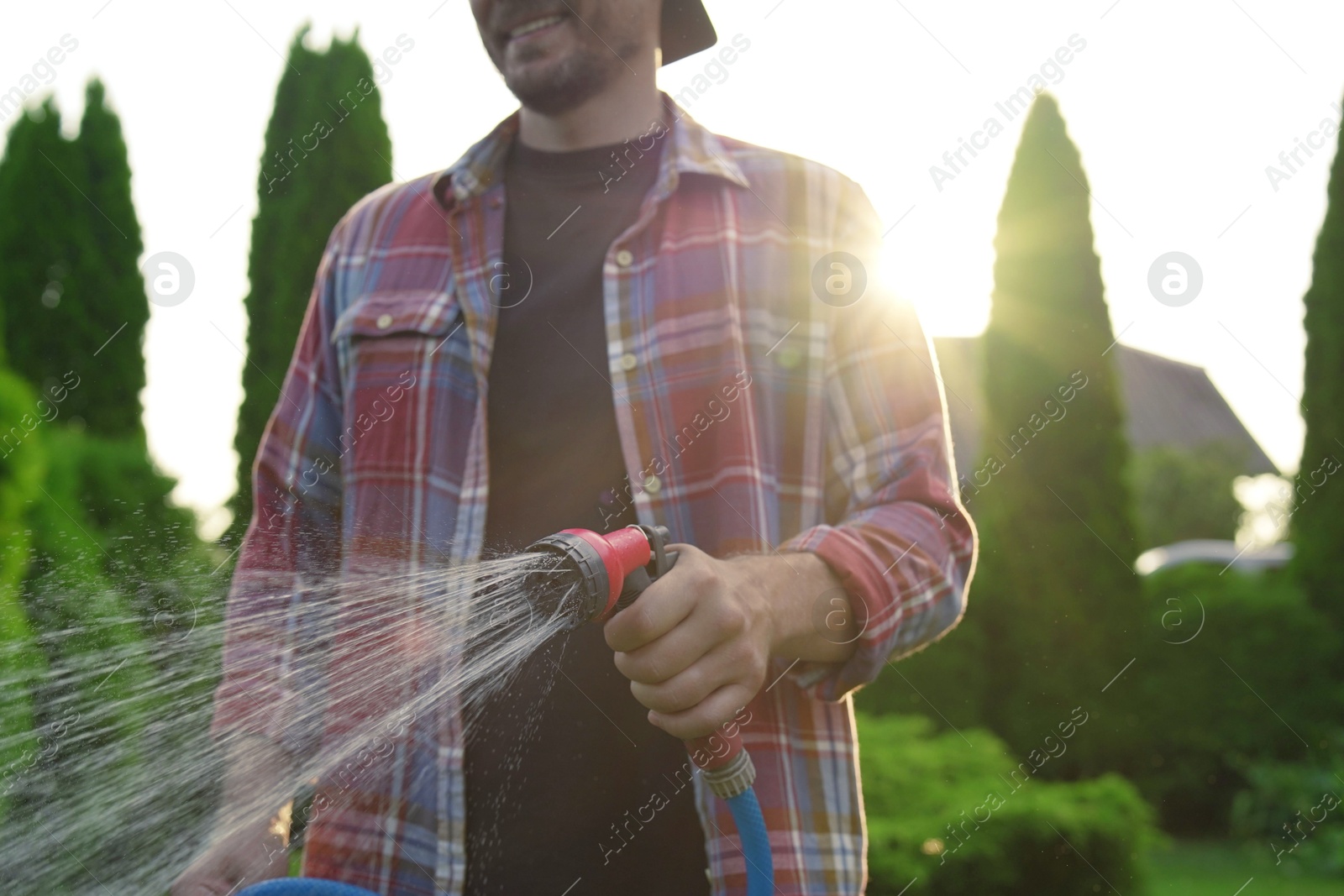 Photo of Man watering lawn with hose in backyard, closeup