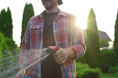 Man watering lawn with hose in backyard, closeup