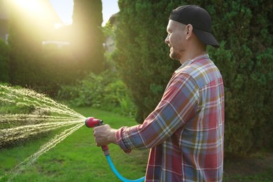 Man watering lawn with hose in backyard