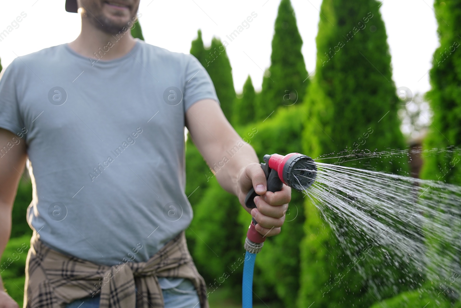 Photo of Man watering lawn with hose in backyard, closeup