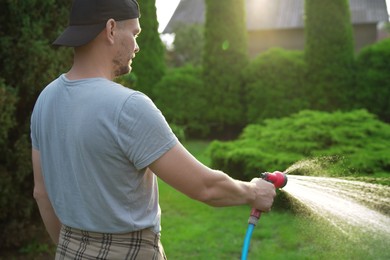 Man watering lawn with hose in backyard