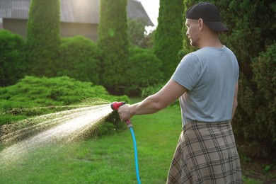 Man watering lawn with hose in backyard