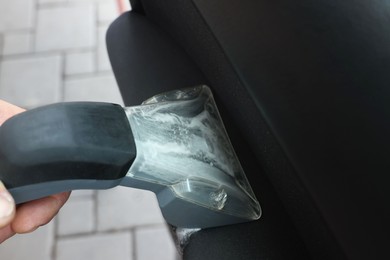 Man cleaning car door with vacuum cleaner outdoors, closeup