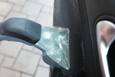 Man cleaning car door with vacuum cleaner outdoors, closeup