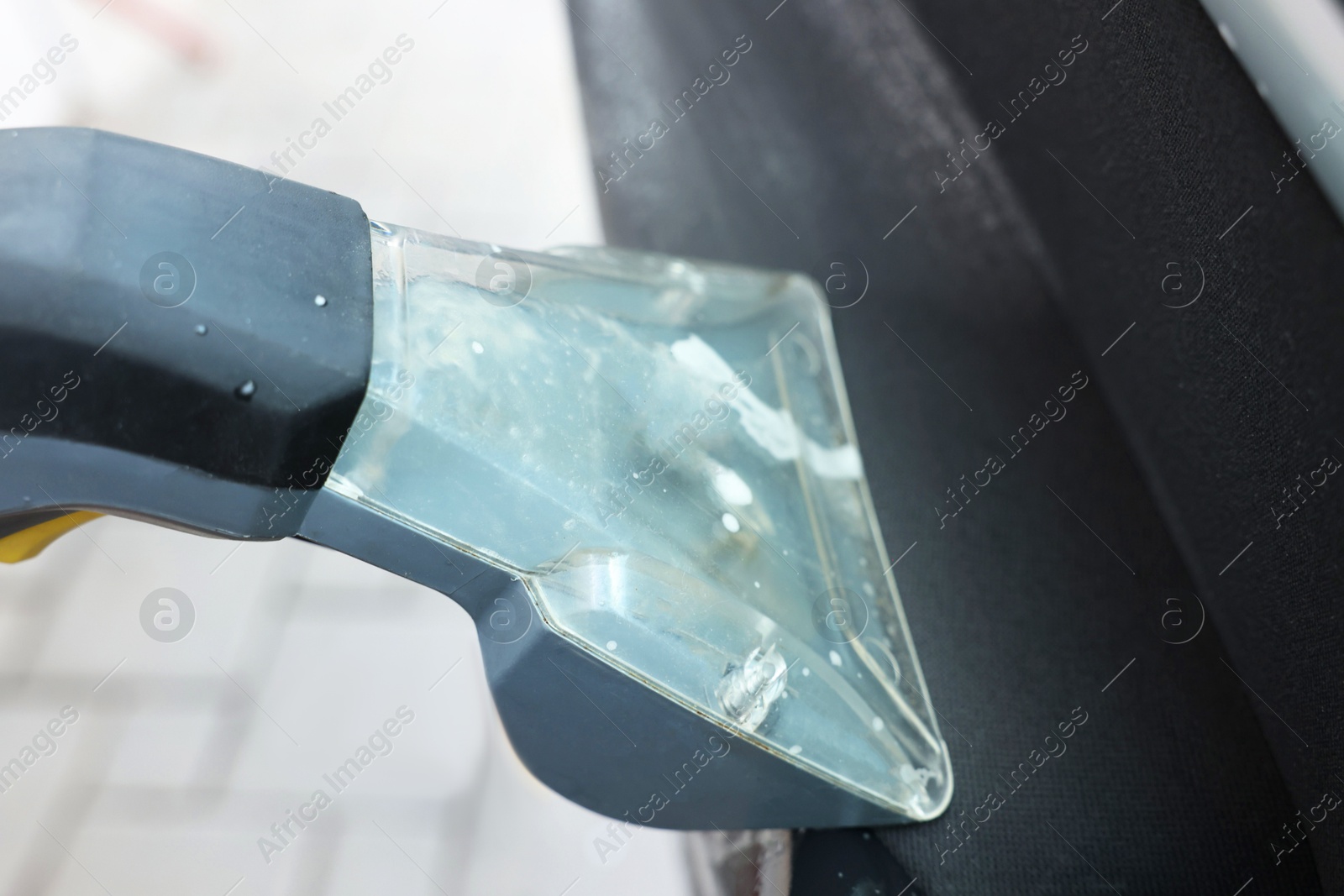 Photo of Man cleaning car door with vacuum cleaner outdoors, closeup