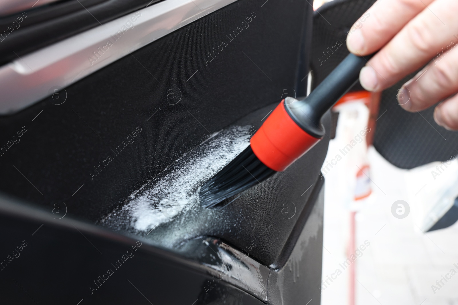 Photo of Man cleaning car door with brush outdoors, closeup