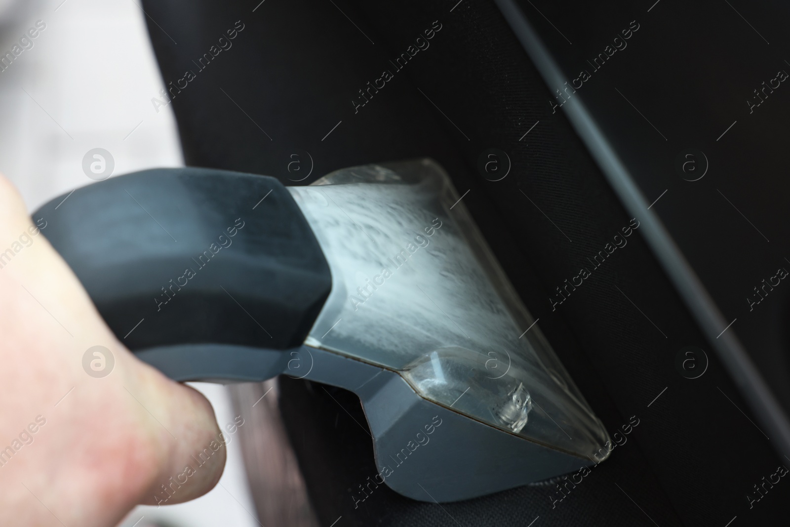 Photo of Man cleaning car door with vacuum cleaner, closeup