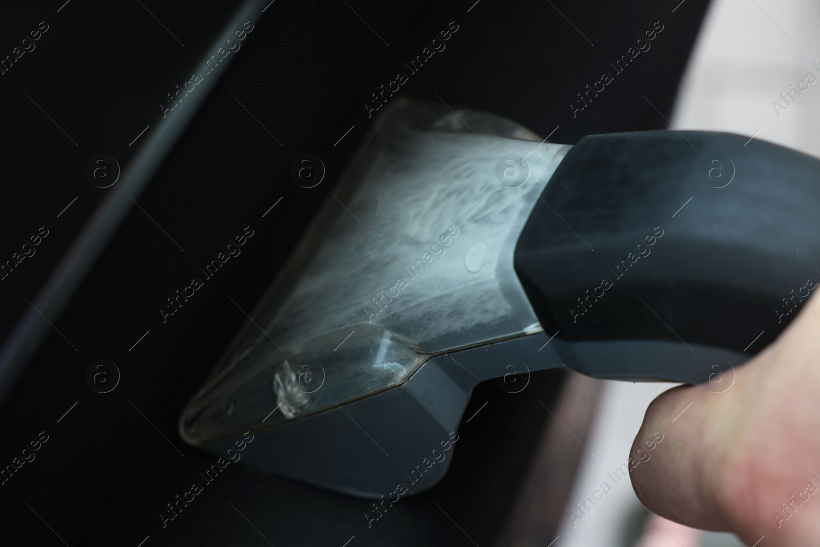 Photo of Man cleaning car door with vacuum cleaner, closeup