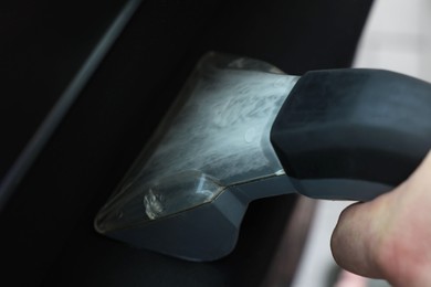 Photo of Man cleaning car door with vacuum cleaner, closeup