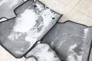 Photo of Car floor mats covered with foam indoors