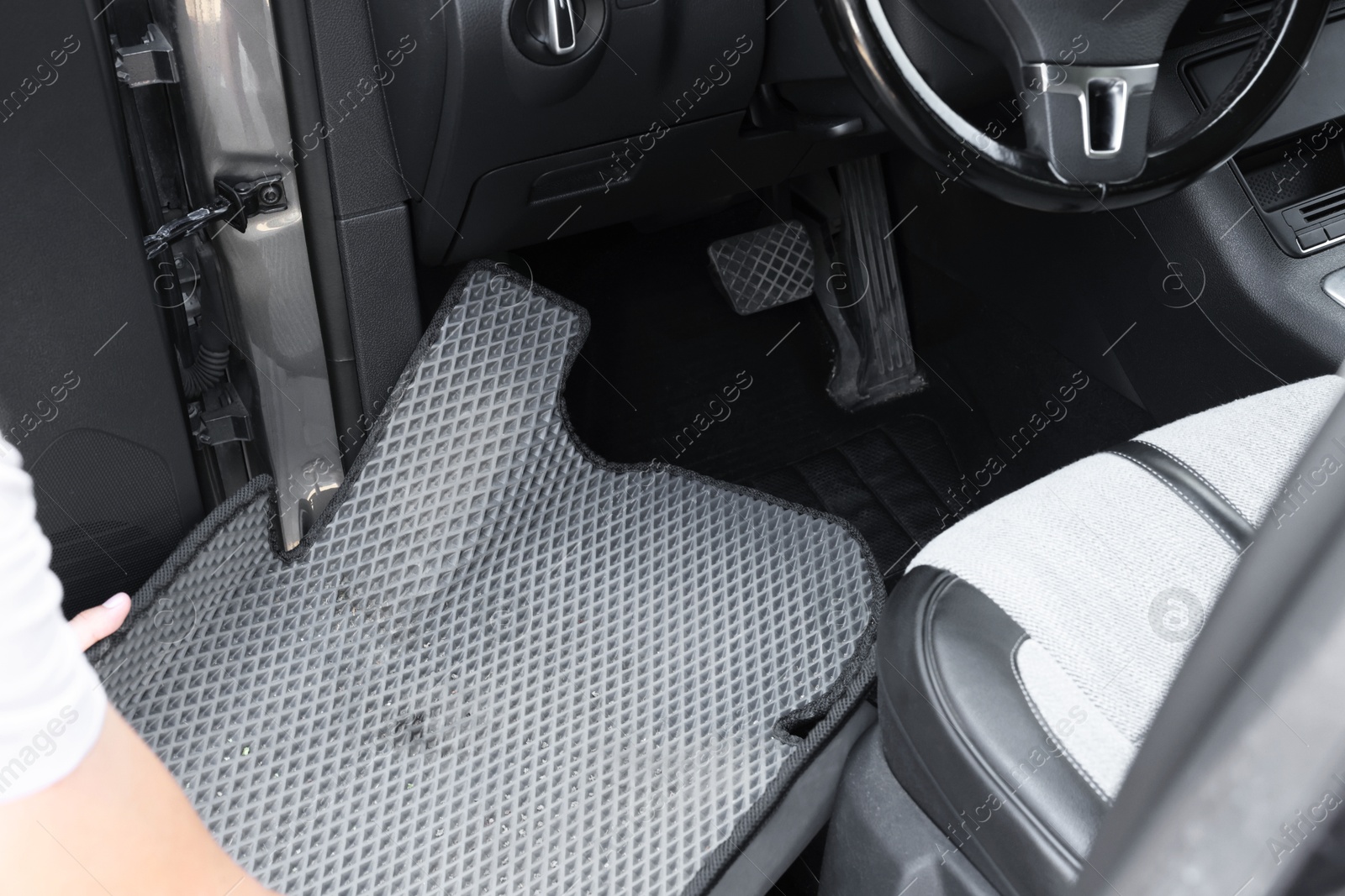 Photo of Man taking grey rubber car mat from auto, closeup