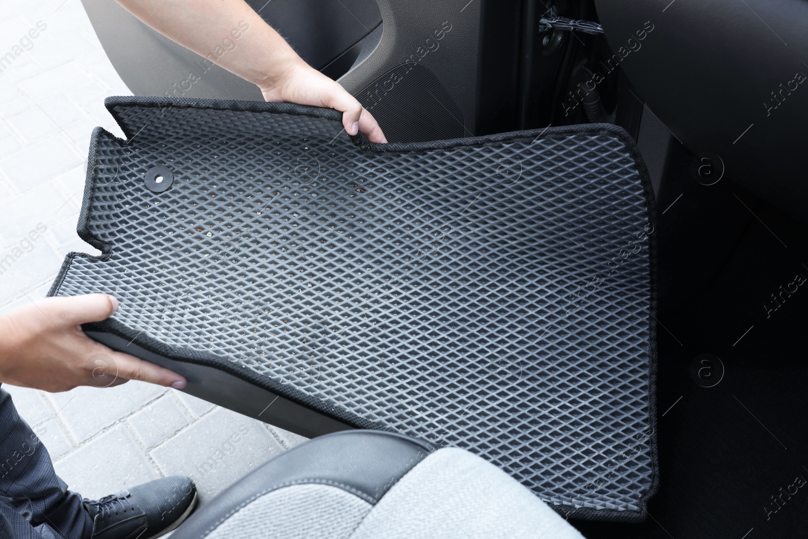 Photo of Man taking grey rubber car mat from auto, closeup