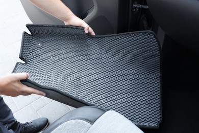 Photo of Man taking grey rubber car mat from auto, closeup