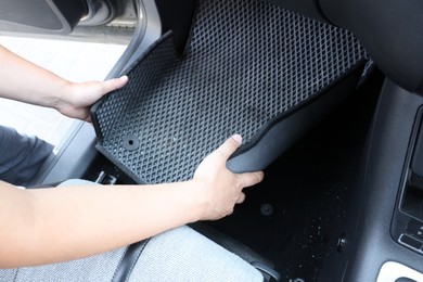 Photo of Man taking grey rubber car mat from auto, closeup