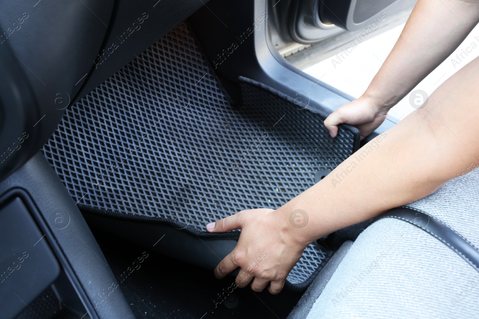 Photo of Man taking grey rubber car mat from auto, closeup