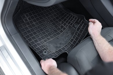 Photo of Man taking black rubber car mat from auto, closeup