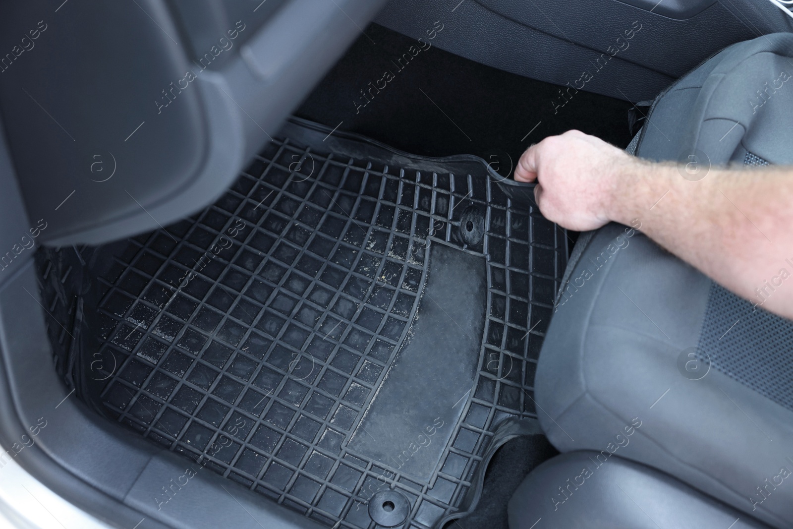 Photo of Man taking black rubber car mat from auto, closeup