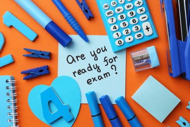 Paper note with question Are You Ready For Exam and stationery on orange background, flat lay