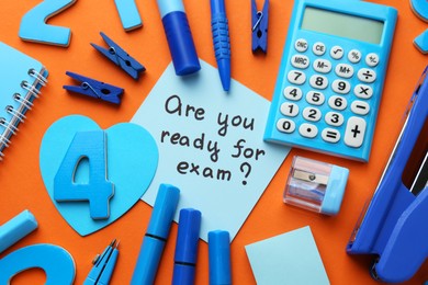 Photo of Paper note with question Are You Ready For Exam and stationery on orange background, flat lay