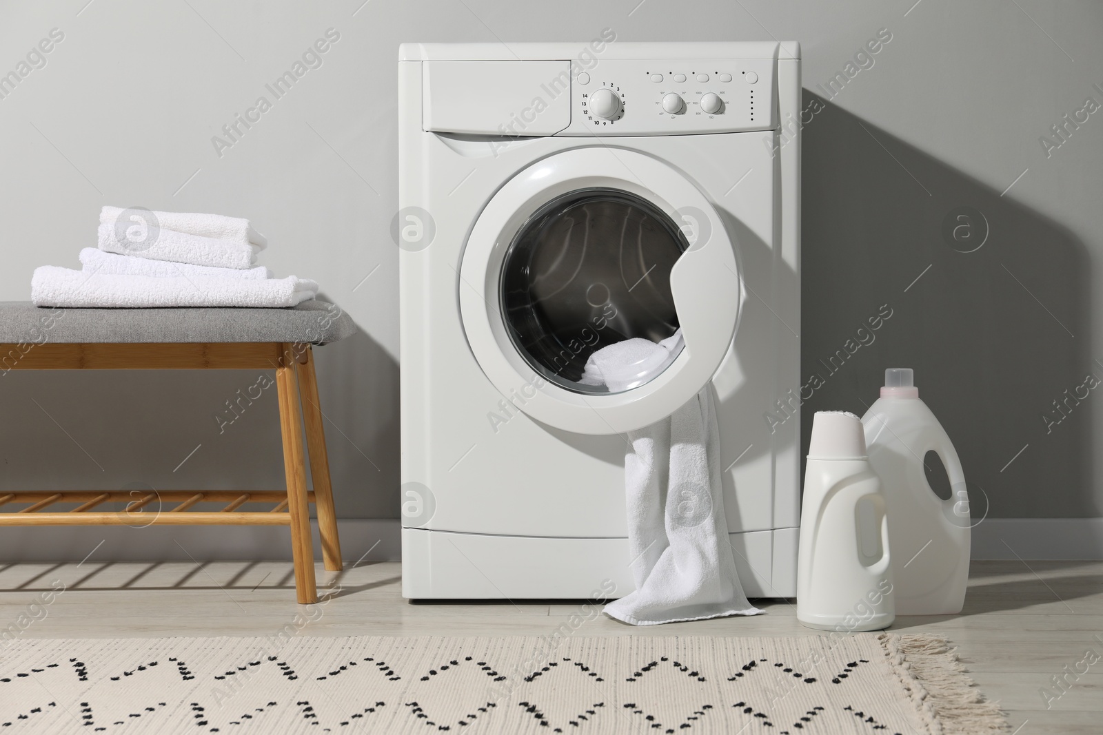 Photo of Washing machine, towels and detergents in laundry room