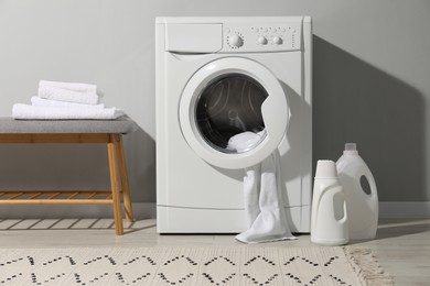 Photo of Washing machine, towels and detergents in laundry room