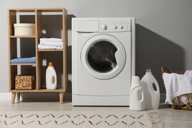 Photo of Washing machine, towels and detergents in laundry room