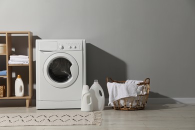 Photo of Washing machine, towels and detergents in laundry room