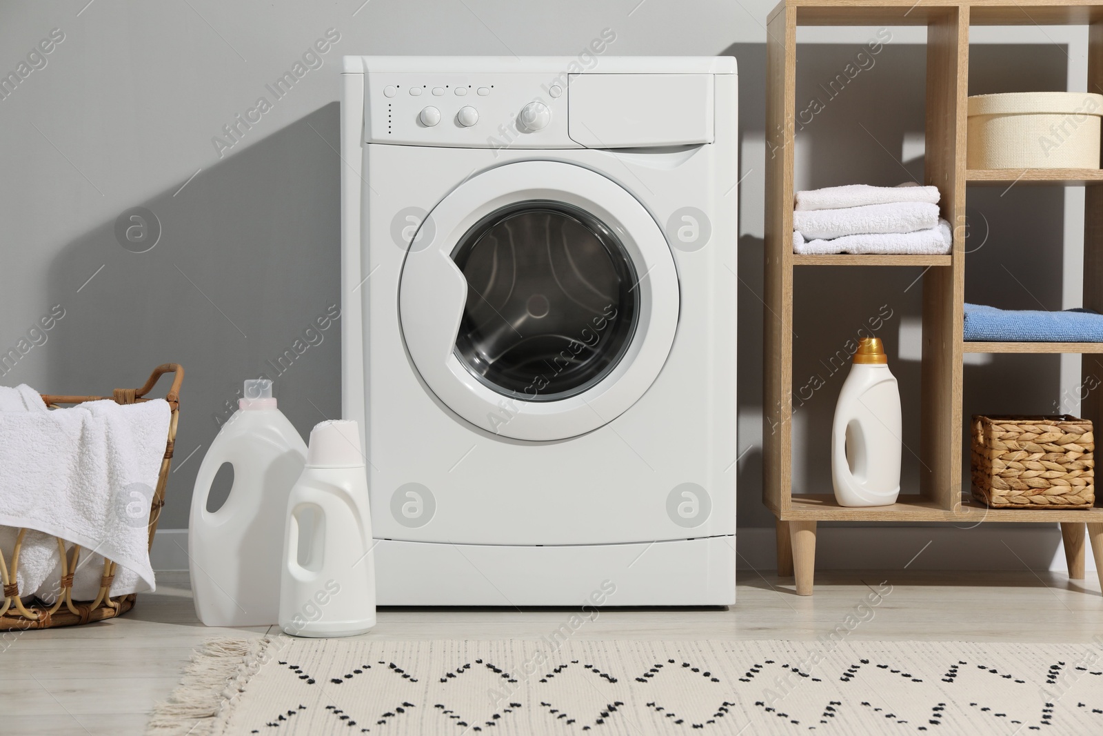 Photo of Washing machine, towels and detergents in laundry room