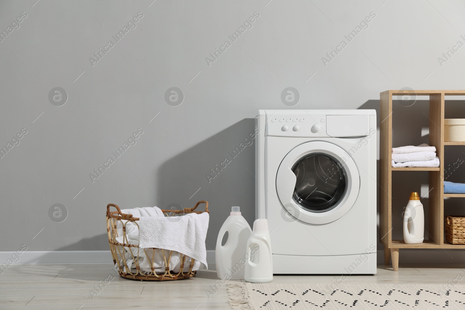 Photo of Washing machine, towels and detergents in laundry room