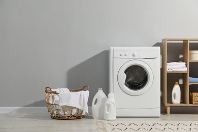 Photo of Washing machine, towels and detergents in laundry room