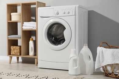 Photo of Washing machine, towels and detergents in laundry room