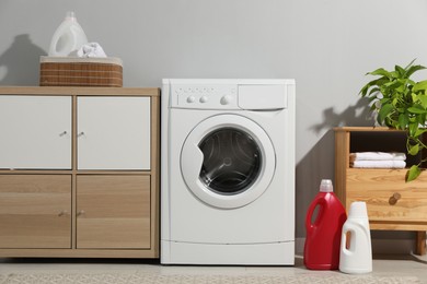 Photo of Washing machine, towels and detergents in laundry room