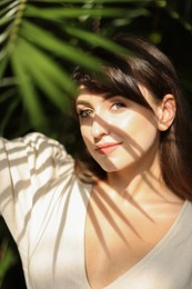 Portrait of beautiful woman in shadow of tropical leaf outdoors