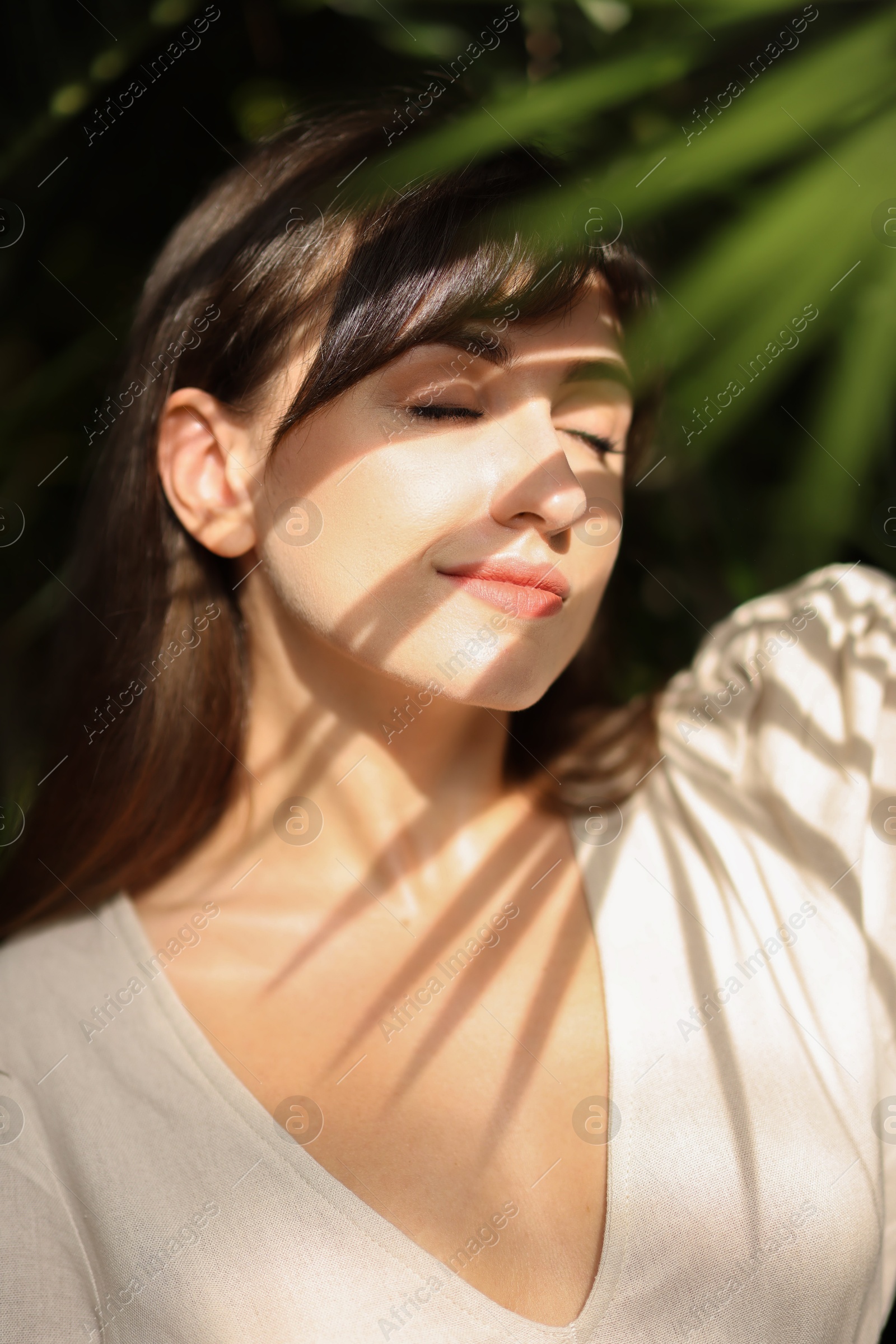 Photo of Portrait of beautiful woman in shadow of tropical leaf outdoors