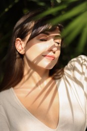 Photo of Portrait of beautiful woman in shadow of tropical leaf outdoors