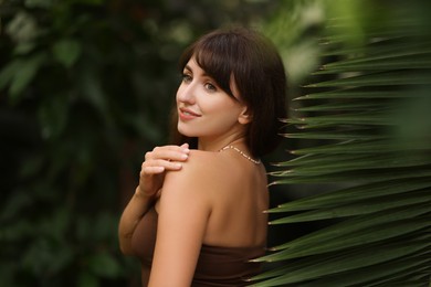 Photo of Portrait of smiling woman near palm leaves outdoors