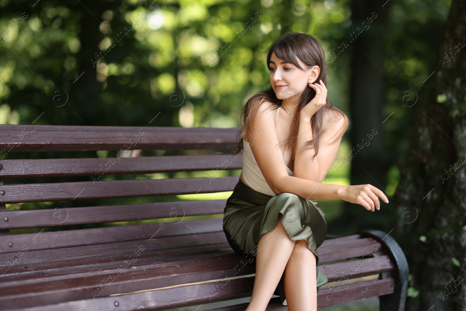 Photo of Beautiful woman sitting on bench in park. Space for text