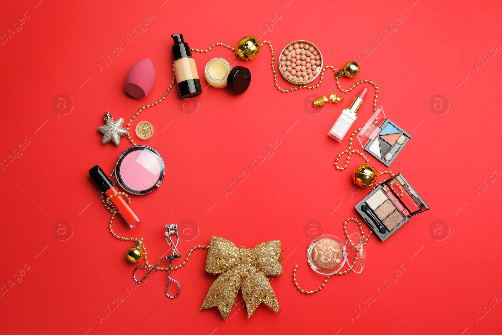 Photo of Frame of makeup products and Christmas decor on red background, flat lay. Space for text