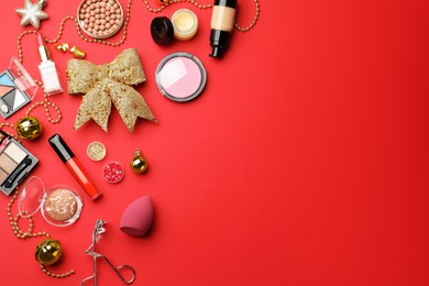 Flat lay composition with makeup products and Christmas decor on red background. Space for text