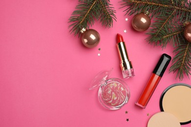 Photo of Flat lay composition with makeup products and Christmas decor on pink background. Space for text