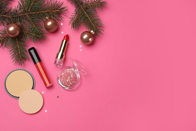 Flat lay composition with makeup products and Christmas decor on pink background. Space for text